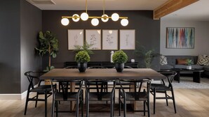 A modern dining area with a rectangular table, black chairs, and potted plants.