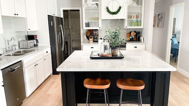 A modern kitchen with white cabinetry, a central island with stools, a refrigerator, and a dishwasher.