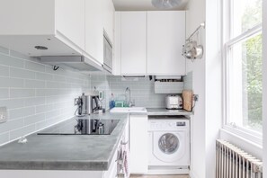 A modern kitchen with a built-in washing machine, a coffee machine, and a toaster.