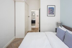 A bedroom with a bed, a bedside lamp, and a framed picture on the wall.