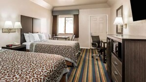 A hotel room with two beds, a desk, a chair, a dresser, and a TV.