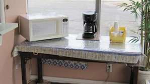 A kitchen counter with a microwave, coffee maker, and a yellow cup holder.