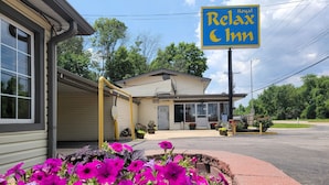 A motel with a sign reading "Royal Relax & Inn" and a parking lot in front.