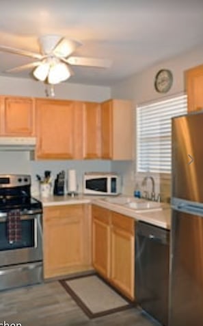 Kitchen equipped with a refrigerator, microwave, and stove, plus a ceiling fan for comfort.