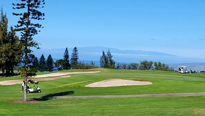 A golf course with bunkers, a flagstick, and a golfer in a cart.