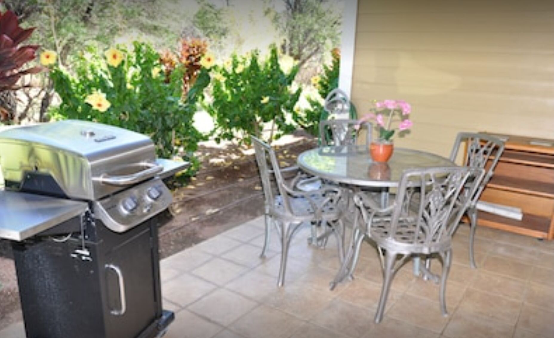 An outdoor patio with a grill, dining table, and chairs.