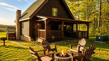 Une cabane en rondins avec un porche, un espace salon extérieur et un foyer.