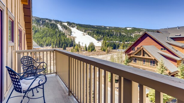 A balcony with a view of a ski slope and forested mountains. - 4 Bedroom Penthouse Condo w Gondola Mountain access! Walk to Ski, Shop or Dine! (Keystone)