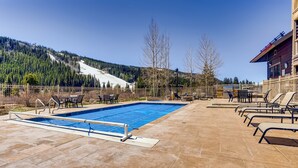 A swimming pool with a diving board, surrounded by lounge chairs and a wooden building with a clock. - 4 Bedroom Penthouse Condo w Gondola Mountain access! Walk to Ski, Shop or Dine! (Keystone)