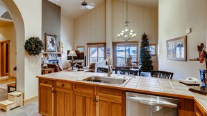 A spacious kitchen with a large island, wooden cabinets, and a chandelier. - 4 Bedroom Penthouse Condo w Gondola Mountain access! Walk to Ski, Shop or Dine! (Keystone)