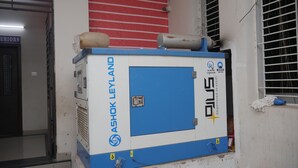 A large industrial machine with the label "ASHOK LEYLAND" and "SILVER" on it, placed against a wall with a window and a red door in the background. - Kubera Service Apartments (Tiruchirappalli)