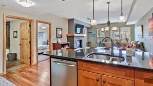 A modern kitchen with a large island, stainless steel appliances, and pendant lighting.