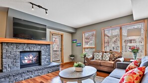 A living room with a stone fireplace, a flat-screen TV, a sofa, and a coffee table.