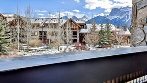 A snow-covered lodge with a mountain backdrop, featuring wooden architecture and a stone wall.