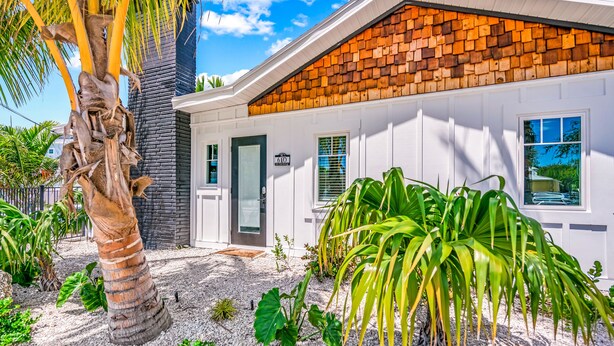 A modern building with a white exterior, a brick gable, and a palm tree in the foreground. - Pelican Post at Anna Maria Island Inn (Bradenton Beach)