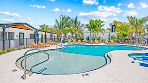 A swimming pool with lounge chairs and palm trees. - Pelican Post at Anna Maria Island Inn (Bradenton Beach)