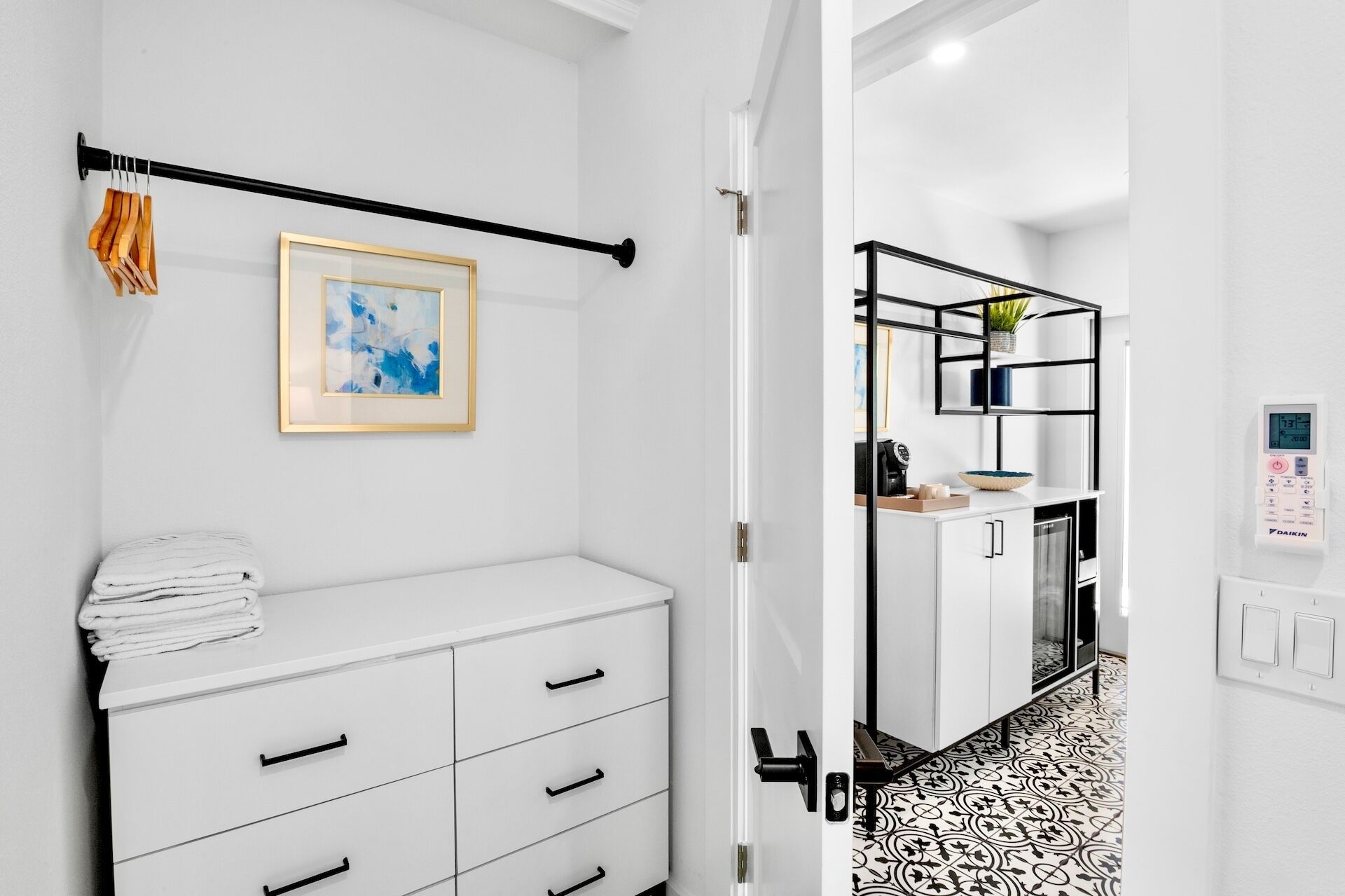 A modern bathroom with a white vanity, a towel rack, and a framed abstract painting.