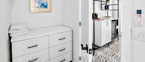 A modern bathroom with a white vanity, a towel rack, and a framed abstract painting.