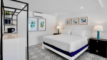 Una habitación de hotel moderna con una cama grande, un suelo con estampado blanco y negro, un armario blanco y obras de arte en las paredes.