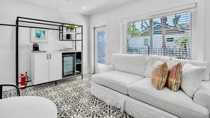 A modern kitchen with white cabinetry, a black-framed shelf, and a coffee machine. - Pelican Post at Anna Maria Island Inn (Bradenton Beach)