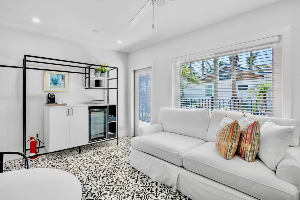 A modern kitchen with white cabinetry, a black-framed shelf, and a coffee machine.