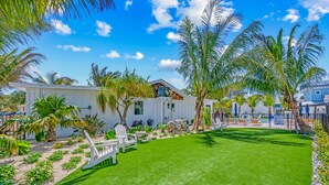 A modern house with a well-maintained lawn, white exterior, and palm trees. - Pelican Post at Anna Maria Island Inn (Bradenton Beach)