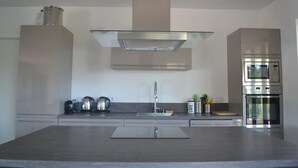 A modern kitchen with a central island, stainless steel appliances, and a minimalist design. - Maremuntagna lux. villa sea view 7 bed swim. pool 10min city (Porto-Vecchio)
