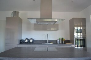 Een moderne keuken met een centraal eiland, roestvrijstalen apparatuur en een minimalistisch ontwerp.