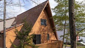 Une cabane en bois avec un toit triangulaire, une petite véranda et une fenêtre.