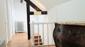 A narrow hallway with wooden flooring, white walls, a white railing, and a dark wooden dresser with ornate handles. - HOUSE in the center of Fécamp - 90 M2 (FECAMP)