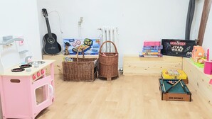 A playroom with a pink toy stove, wicker baskets, and various children's toys. - HOUSE in the center of Fécamp - 90 M2 (FECAMP)