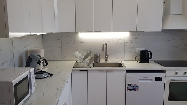 A compact kitchen with white cabinets, a built-in microwave, a coffee maker, a kettle, and a dishwasher. - HOUSE in the center of Fécamp - 90 M2 (FECAMP)