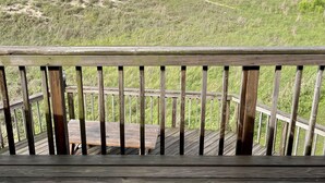 Une terrasse en bois offrant une vue sur une plage de sable et l’océan.