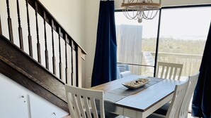 Un coin repas avec une table en bois, des chaises blanches et un tapis à motifs.