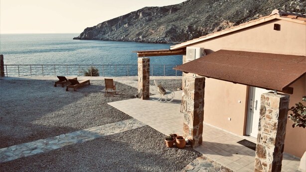 Ein Küsteneigentum mit Terrasse, Sitzgelegenheiten im Freien und Blick auf das Meer.