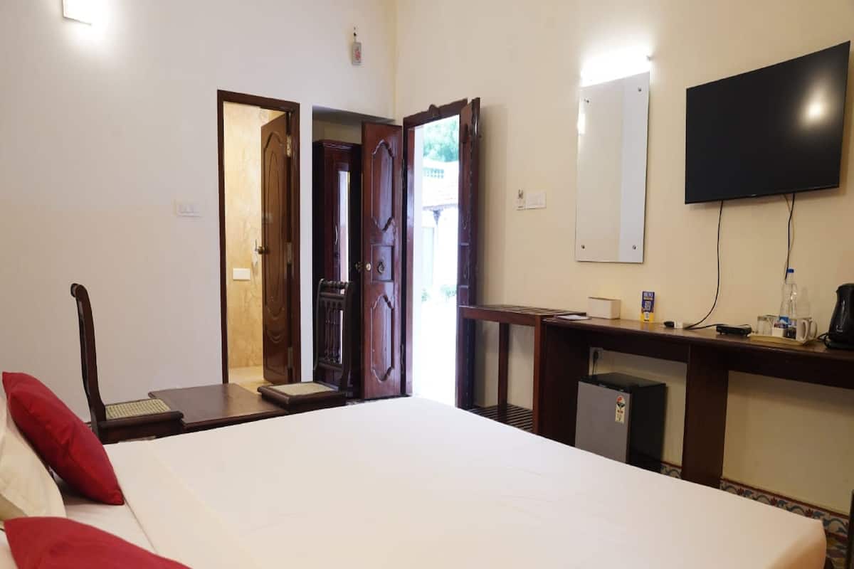 Ein Hotelzimmer mit einem großen Bett, einem Schreibtisch mit Stuhl, einem an der Wand befestigten Fernseher und einem kleinen Kühlschrank.