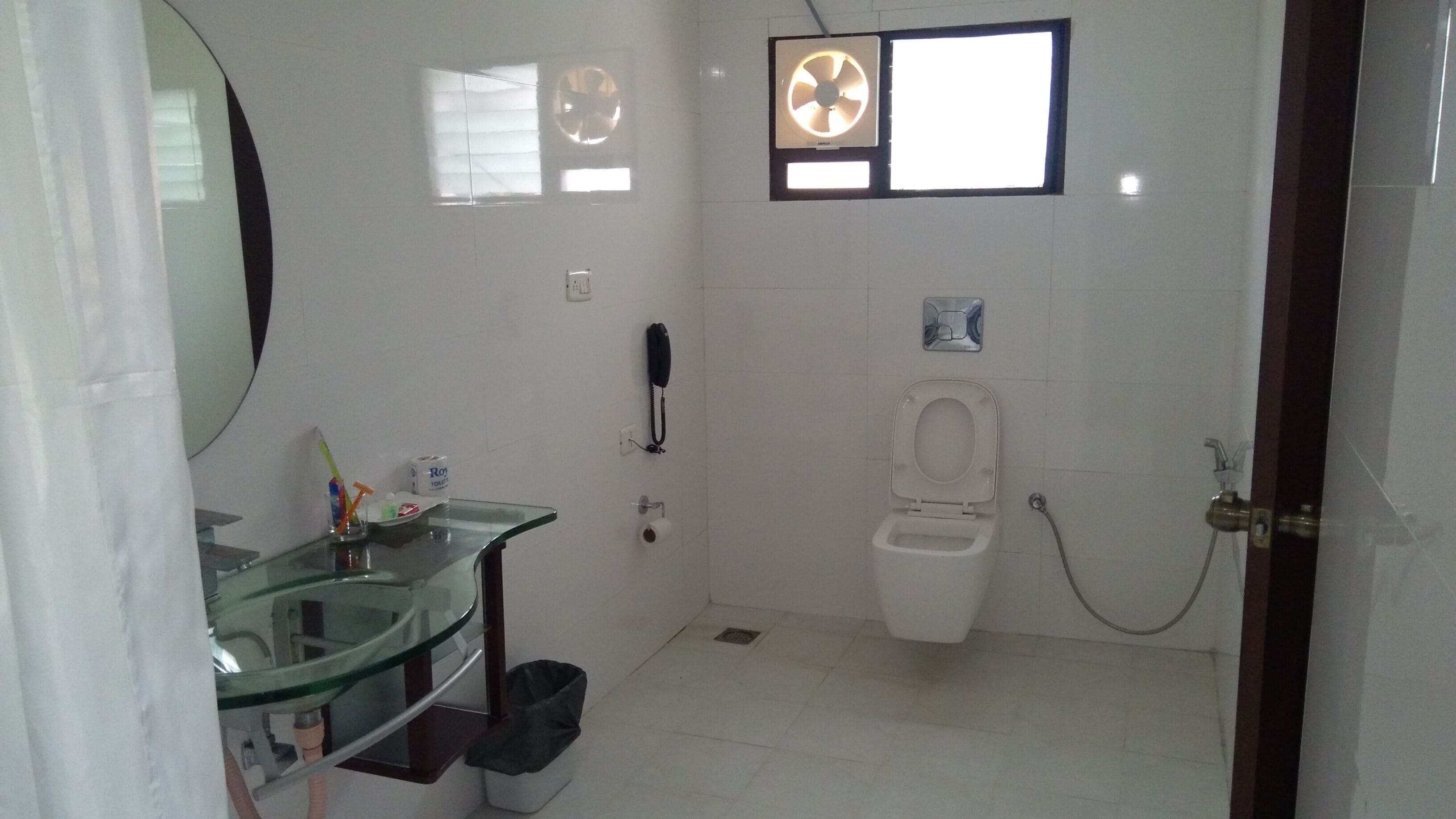 A bathroom with a glass sink, toilet, and a shower.