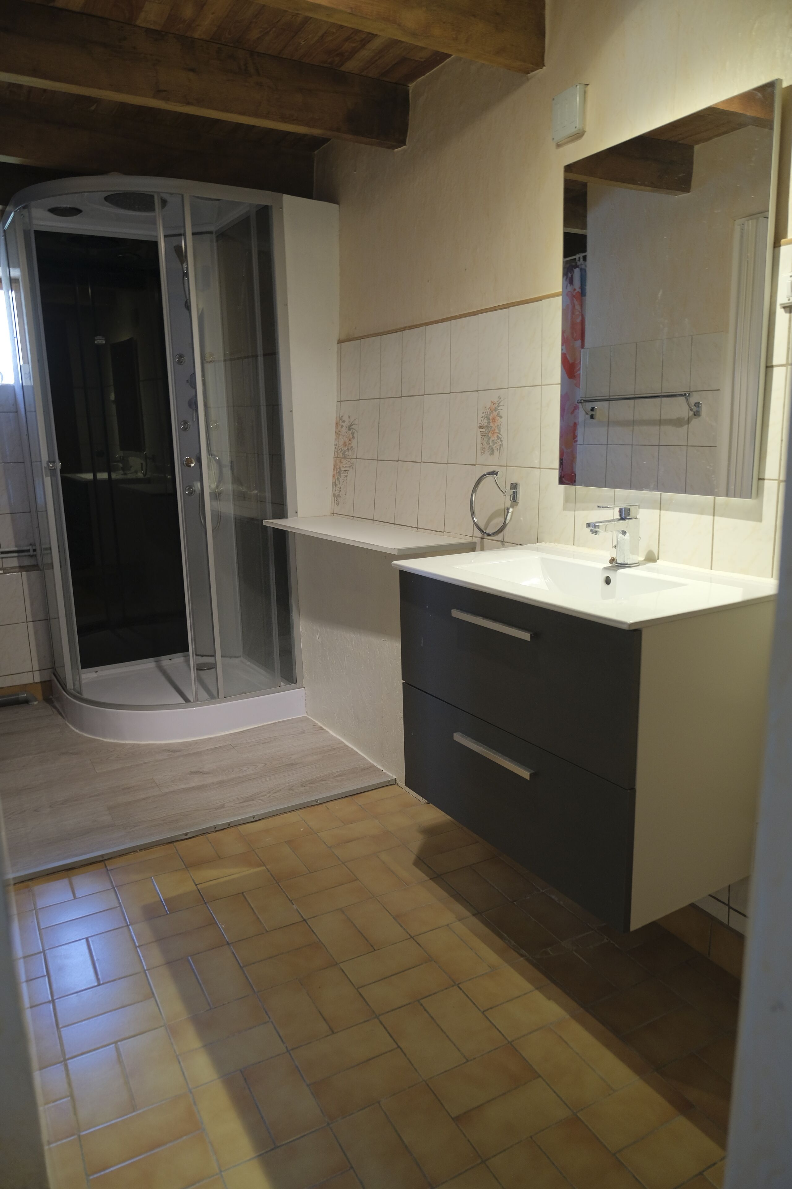 Un baño con ducha, lavamanos y espejo.