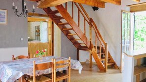 Ein Essbereich mit einer Holztreppe, einem Tisch mit Tischdecke und einem Kronleuchter.