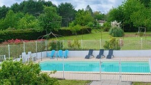 Ein rechteckiger Pool mit weißem Zaun, umgeben von einer Rasenfläche und Bäumen.