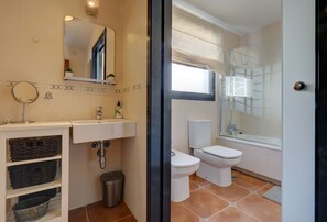 A modern bathroom with a white sink, mirror, and toilet. There is a trash bin and a window with a view. - Villa in Puerto Marina with private and heated pool (Benalmádena)