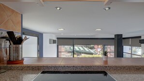 Eine moderne Küche mit Granitarbeitsplatten, einer Edelstahlspüle und einem Fenster mit Blick ins Freie.