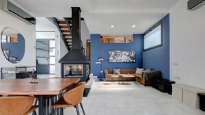 Ein modernes Wohnzimmer mit Kamin, einem Essbereich mit Holztisch und Stühlen sowie einer blauen Akzentwand.
