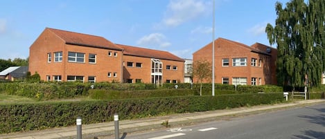 A modern brick building with a flat roof, large windows, and a central entrance.