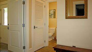 A hallway with closed doors, a toilet visible in the background, and a mirror on the wall.