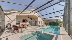 Una piscina al aire libre techada con sillas de descanso y un ventilador de techo.