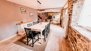 Un espace repas avec une longue table, des chaises et une cuisine en arrière-plan.