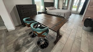 Une chambre à coucher moderne avec un lit en bois, une table à manger avec des chaises et une grande fenêtre.