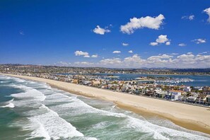 Paisagem costeira com praia, edifícios e um porto de iates.