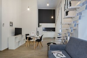 Un apartamento moderno con comedor, cocina y sala de estar con sofá y televisor.